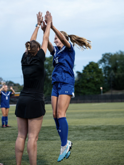 Kelsey Etherton and Katie Bucher (11) share a high five on the field.